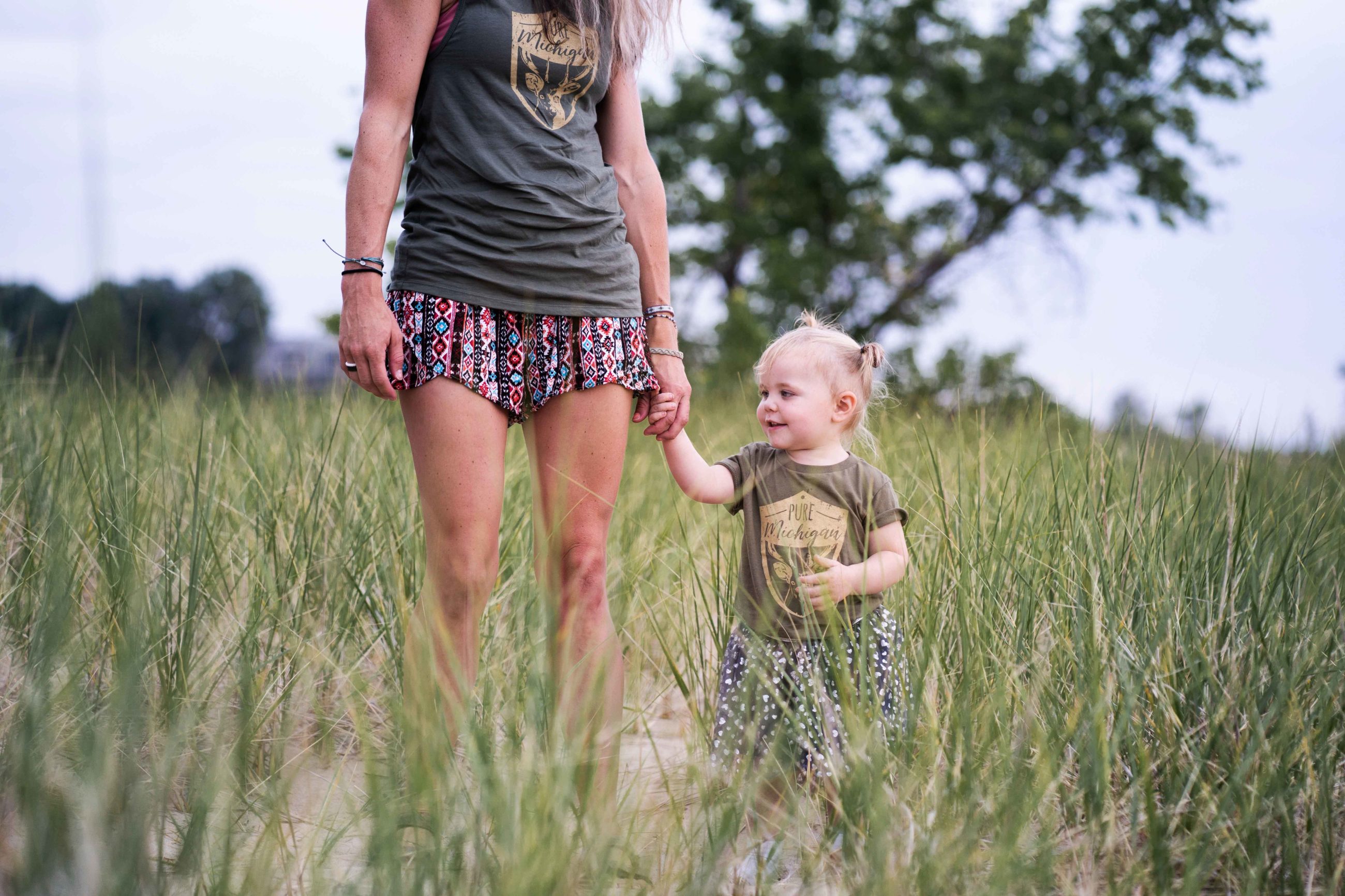 mère dans un champs l'été avec sa petite fille qu'elle tien par la main