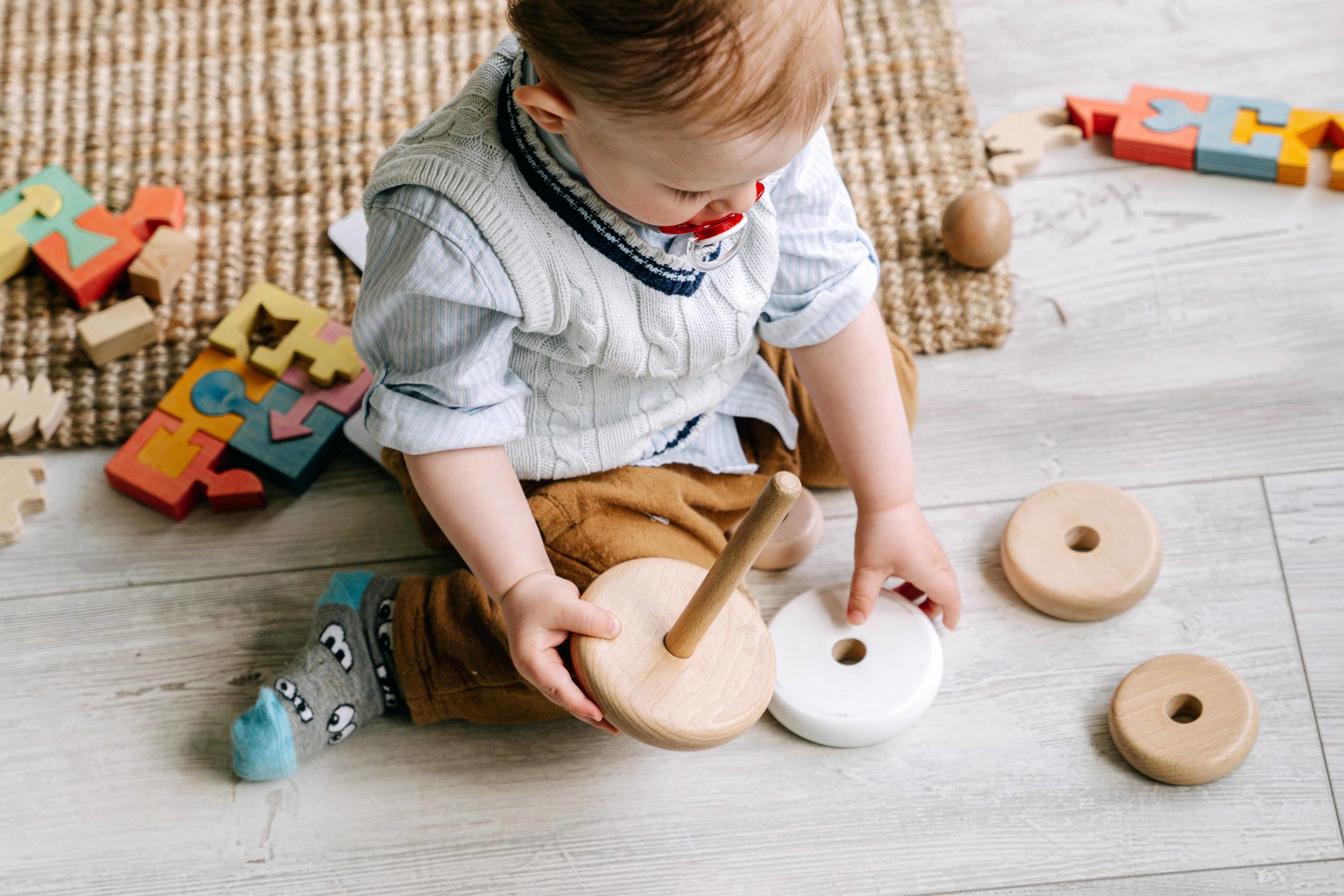 enfant assis par terre avec des jouets en bois