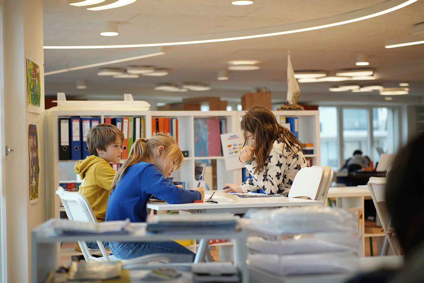 trois enfants en train de faire un exercice en classe