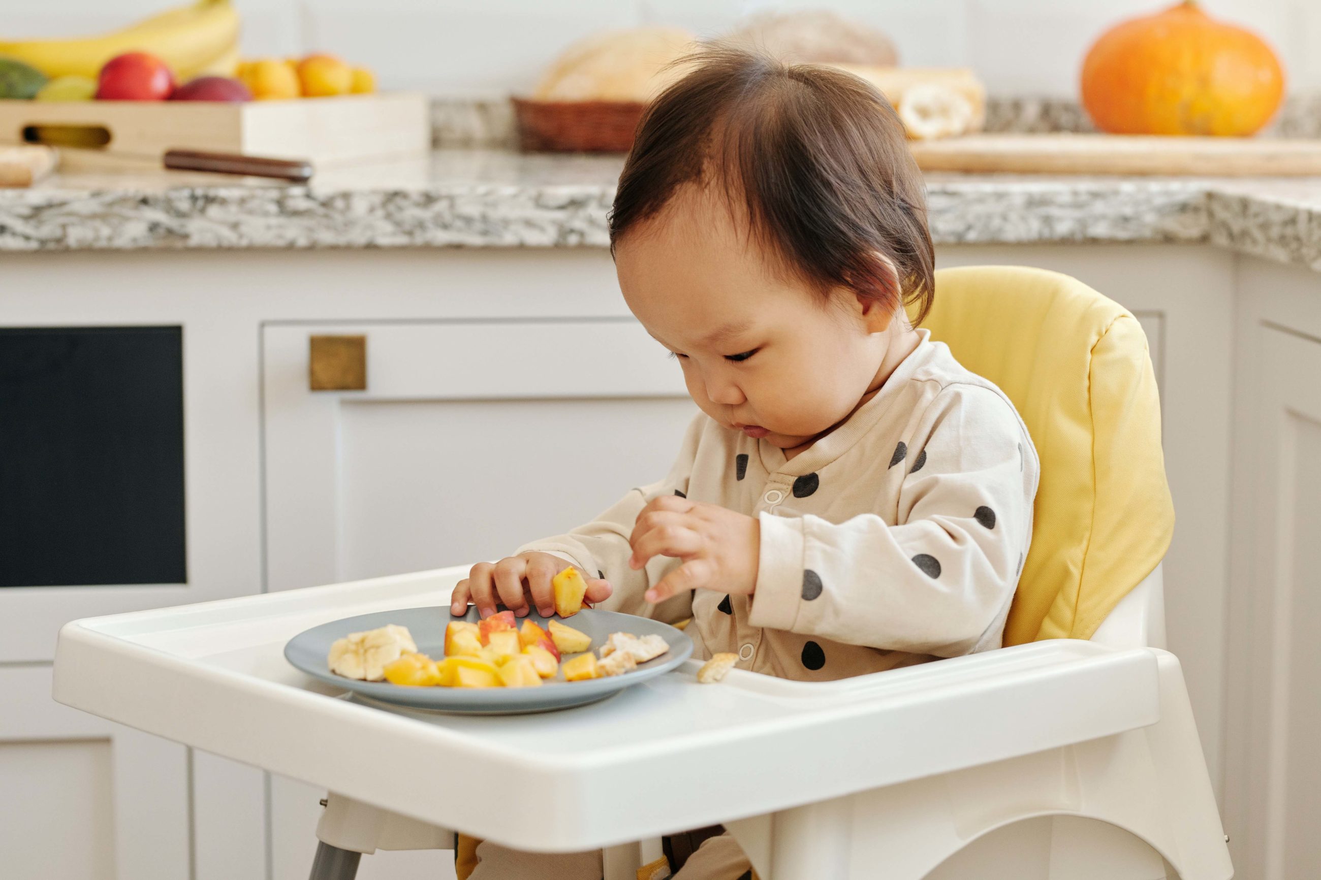 enfant assis dans sa chaise haute en train de manger