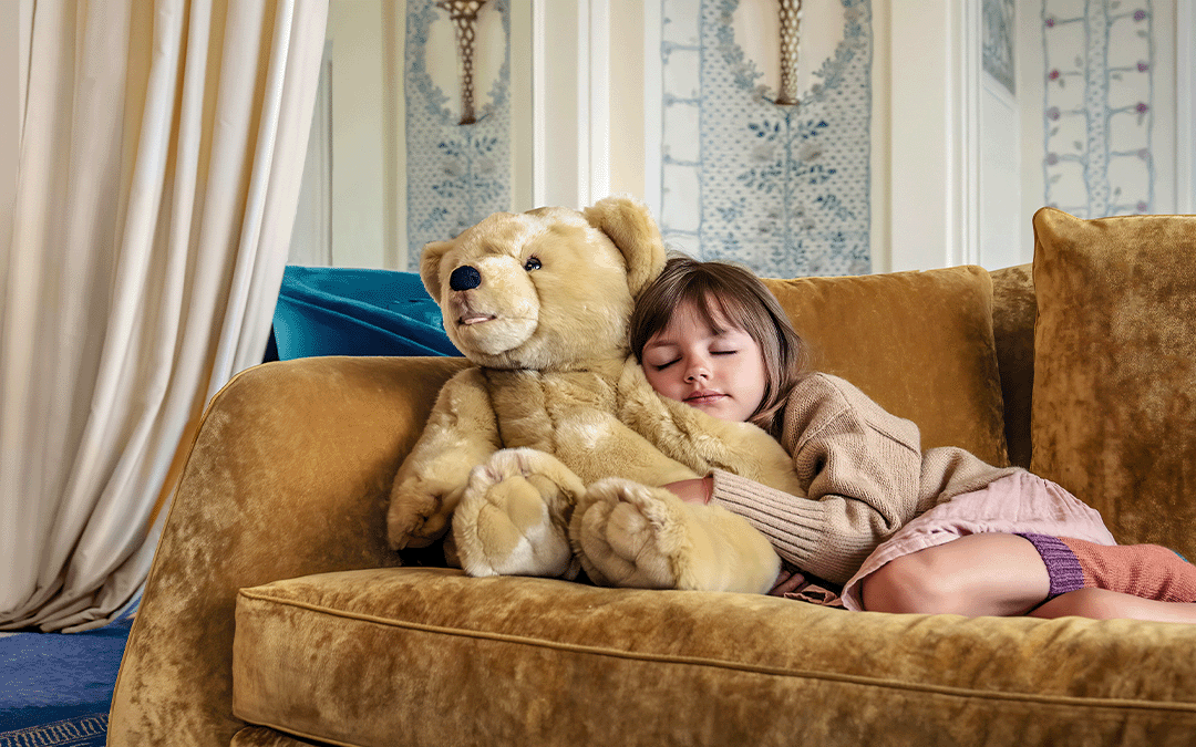 petite fille couchée sur un canapé avec une énorme peluche